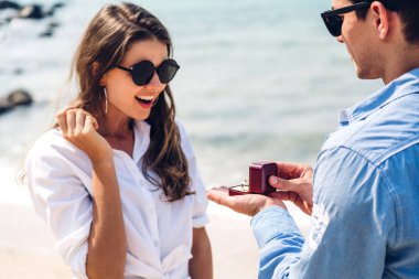 Genç yakışıklı romantik adam sevgilisine sürpriz olsun diye elmas yüzük veriyor ve Sevgililer Günü 'nde tropik plajda konuşuyor.