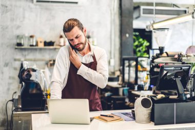Gülümseme portresi yakışıklı sakallı barista başlangıçta dizüstü bilgisayarla çalışan küçük işletme sahibi bir kafede tezgahın arkasındaki müşteriden emir alır.