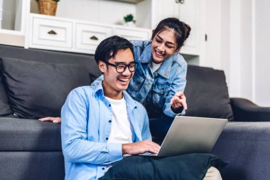 Genç Asyalı çift dizüstü bilgisayarla rahatlıyor ve video konferansında online sohbet ediyorlar. Yaratıcı iş çifti strateji analizi ve evde beyin fırtınası planlıyor.