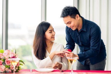 Yakışıklı, romantik Asyalı bir adam sevgilisine sürpriz yapmak için elmas yüzük veriyor ve sevgililer gününde restoranda konuşuyor.