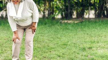 Hasta, yaşlı, yaşlı, kas sakatlığı olan bacağına dokunan yaşlı bir Asyalı kadın parkta diz ağrısı çekiyor. Fiziksel yaralanma ve sağlık sorunları.