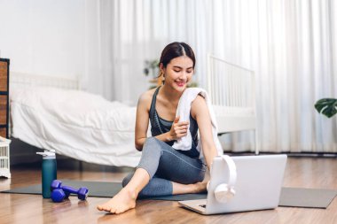 Portre sporu spor, spor kıyafetleri içinde ince kadın, rahatlama ve yoga yapan kız, yatak odasında dizüstü bilgisayarla spor yapıyor. Diyet konsepti. Fitness ve sağlıklı.