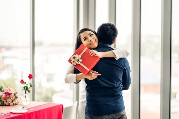 Romantic sweet couple having fun and smiling while celebrating enjoying valentines day time together.handsome man giving gift box surprise to girlfriend in valentines day