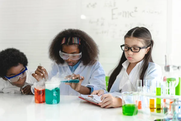 Group of teenage student learn and study doing a chemical experiment and holding test tube in hand in the experiment laboratory class on table at school.Education concept