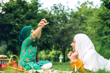Mutlu din portresi mutlu Asyalı İslami aile, Müslüman anne ve tesettürlü küçük kız çocuğu gülümsüyor ve yaz parkında iyi vakit geçiriyor.