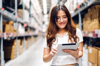 Tablet üzerindeki portre mühendisi kadın nakliyat emri ayrıntıları raflarda malzeme ve malzeme kontrolü fabrika deposunda malzeme envanteriyle birlikte. Lojistik endüstrisi ve iş ihracatı