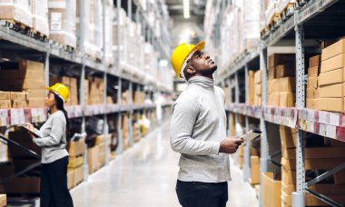 İki Afro-Amerikan mühendis ekibinin portresi tablet üzerindeki sevkiyat emri. Ürün ve erzakları fabrika deposunda malzeme stoklarıyla birlikte kontrol et. Lojistik endüstrisi ve ticari ihracat.