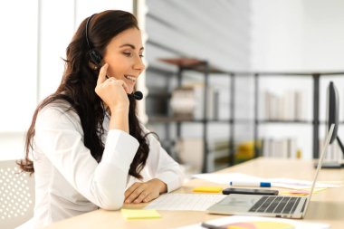 Mutlu çağrı merkezi gülümseyen iş kadını operatörü grubu çağrı merkezinin bilgisayarında çalışan ve kulaklıkla konuşan ekip telefon hizmetlerini desteklemeye yardım eder.