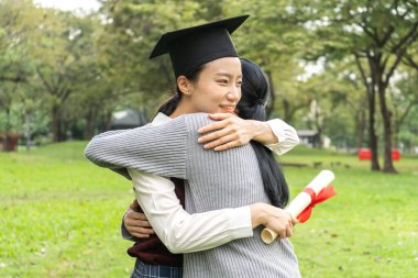 Başarılı öğrenci genç kadın ve bekarlığa veda önlük ile diploma mezun arkadaşı Üniversitesi'nde sarılma. Mezuniyet ve eğitim kavramı kutlama