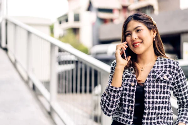 Portrait of smiling happy beauty asian business woman relaxing using digital technology smartphone.Young asian girl work call and talk with friend business team at city