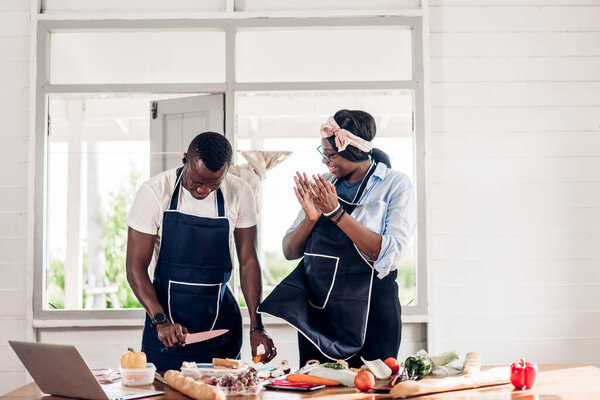 Portrait of love african american couple having fun cooking food together with fresh vegetable salad and sandwich ingredients to prepare the yummy eating in kitchen at home