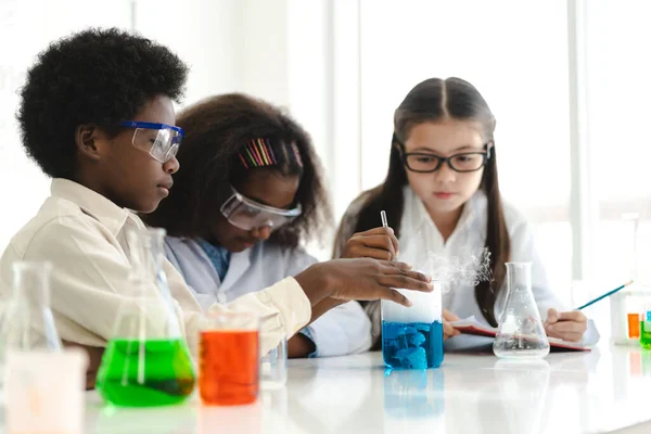 Group of teenage student learn and study doing a chemical experiment and holding test tube in hand in the experiment laboratory class on table at school.Education concept