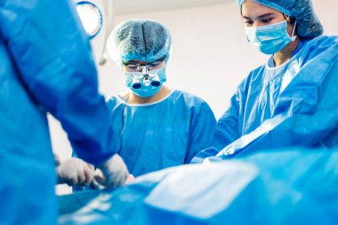 Profesyonel anestezi uzmanı doktor tıp ekibi ve asistanı modern hastane acil servisinde cerrahi ekipmanla jinekolojik ameliyata hazırlanıyor.