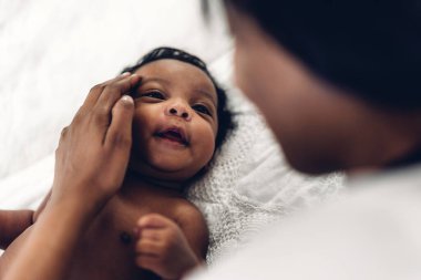 Mutlu bir aşk portresi Afro-Amerikan anne, sevimli bir Afrikalı Amerikalı bebekle oynuyor. Anne, tatlı oğluyla beyaz bir odada iyi vakit geçiriyor. Siyah aile sevgisi.