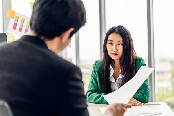 Asian business man and woman meeting analyzing and discussing strategy with startup project.Creative business people talk plan and brainstorm with document in office.Teamwork