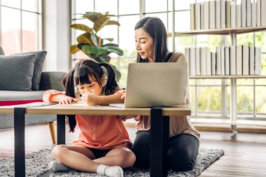 Anne ve Asyalı küçük kız öğreniyor ve online eğitim ile bilgisayar incelemesi yapıyor. Öğrenci evde eğitim bilgisini arıyor. Eğitim