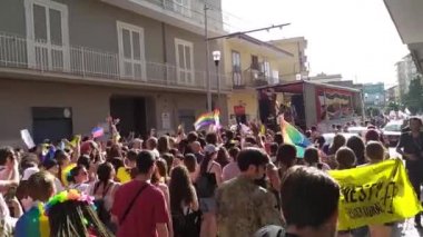 Aversa şehrinin sokakları boyunca düzenlenen Aversa Gururu 'nun bayrak ve pankartlarıyla düzenlenen törene katılan genç katılımcılar. Aversa, İtalya, 26 Haziran 2022.