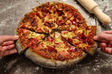 Gençler gri hamurla pişirilmiş yenilikçi pizzaları paylaşıyorlar. Sağlıklı beslenme, ev yapımı İtalyan mutfağı..