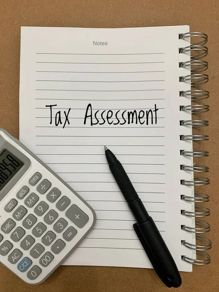 計算機とペンの背景を持つノートパッド上の税務評価テキスト — ストック写真