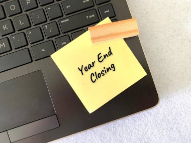 Tahta tuğla ve dizüstü bilgisayar arkaplanlı yapışkan notla yıl sonu kapanışı metni