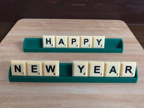 Deseando Feliz Año Nuevo usando scrabble con madera marrón y fondo de pared —  Fotos de Stock