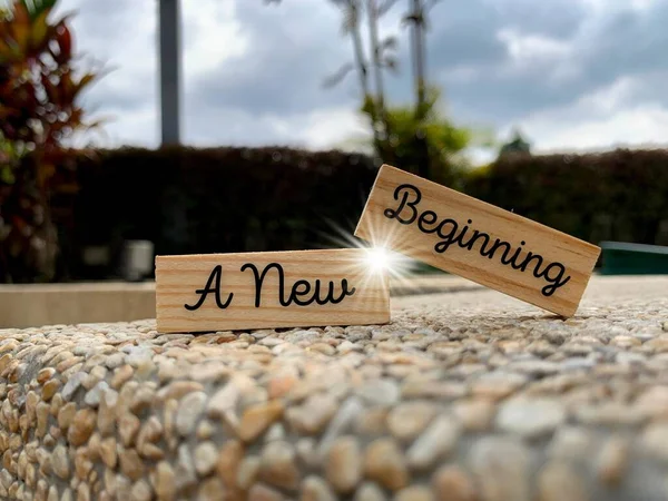 A new beginning text on wooden blocks with beautiful nature background with small floor rocks — Stock Photo, Image