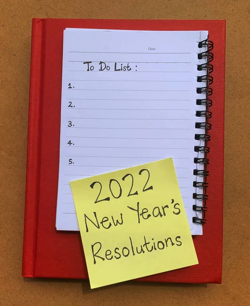 Para hacer la lista escrita en un bloc de notas con una nota adhesiva que desea 2022 resoluciones de año nuevo. Color rojo cubierta libro fondo — Foto de Stock