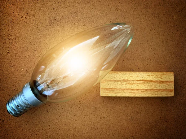 Dřevěný špalek se zářící žárovkou. — Stock fotografie