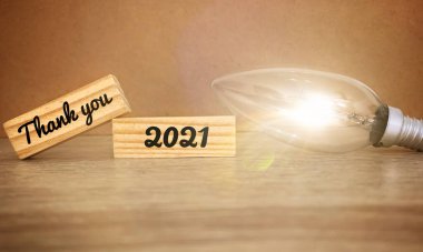 Görüntü: Teşekkür ederim 2021 Metin: Ahşap bloklar ve parlak ampul arka planı.