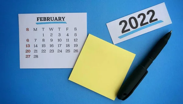 White February 2022 calendar with pen, sticky note and blue background. 2022 New Year Concept — Stock Photo, Image