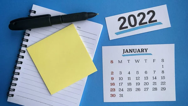 White January 2022 calendar with sticky note, black pen and notepad background. 2022 New Year Concept — Stock Photo, Image