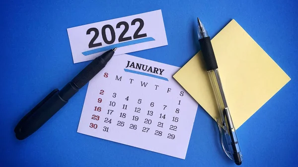 White January 2022 calendar with pens and sticky note. 2022 New Year Concept — Zdjęcie stockowe