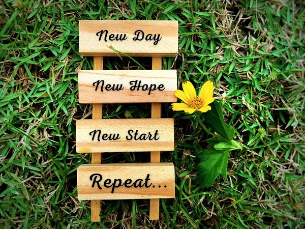 Motivatív és inspiráló idézetek fablokkokra - Új nap, új remény, új kezdet és ismétlés. Zöld fűvel és virágos háttérrel. Motivációs koncepció. — Stock Fotó