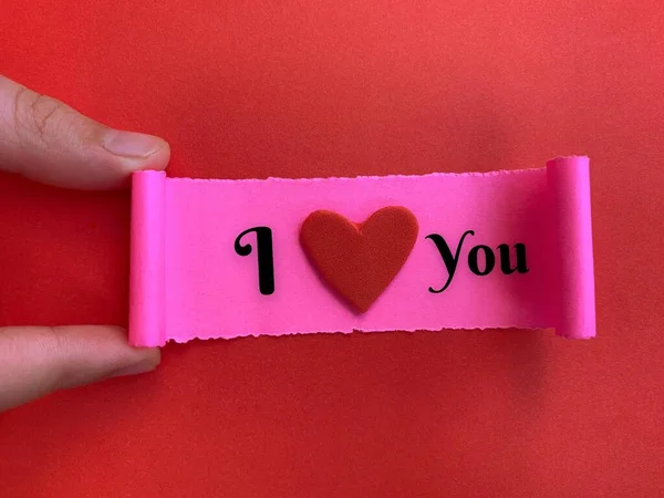 I love you text on a small piece of torn paper with red color background. Valentines Day concept. — стокове фото