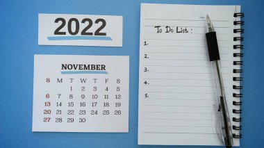 To do list text written on notepad for November 2022 with pen and blue background. 2022 new year concept.