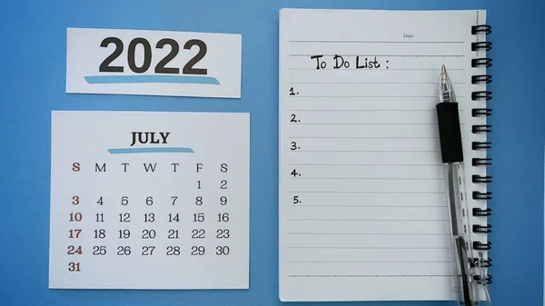 To do list text on note book with pen and July calendar month 2022 background. 2022 new year concept. — Zdjęcie stockowe