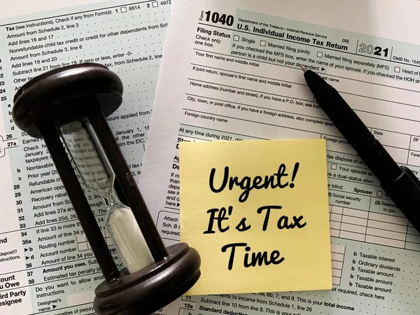 Its tax time on sticky note with 1040 tax form, pen and minutes glass timer background. — 图库照片
