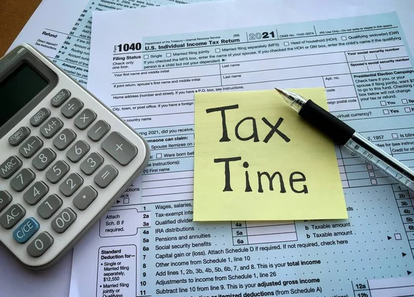 Close up on tax time text on sticky note with 1040 tax form, pen and calculator. Tax concept. — Stockfoto