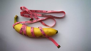Diet and weight loss Concept. Top view of banana, weight scale measure tap and white background.