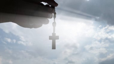 Parlak güneşli kutsal tespihi tutan el. Hıristiyanlık kavramı.