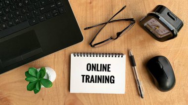 Dizüstü bilgisayarı, kalemi, faresi, bitkisi, gözlüğü ve kahverengi masa arkaplanı olan çevrimiçi eğitim metni. Çevrimiçi iş kavramı