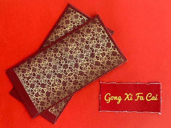 Темний червоний і золотий конверти з китайським новорічним текстом на пошматованому червоному папері. Святкування.. — стокове фото