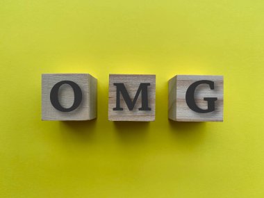 Tahta bloklar üzerinde sarı arkaplan ile OMG alfabesi.