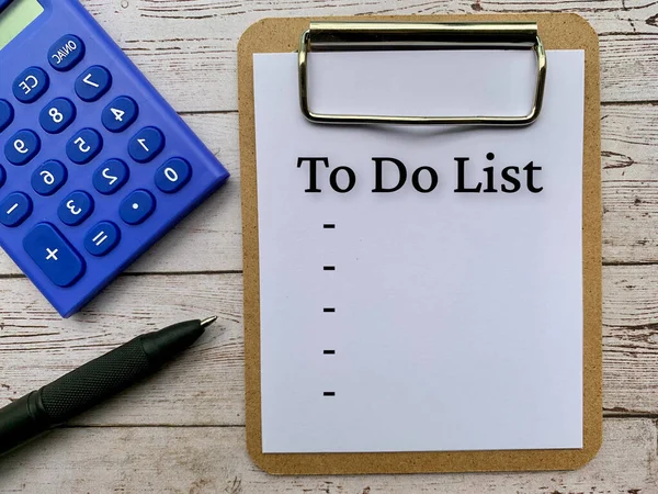 Not defterindeki metnin üst görünümü - yapılacaklar listesi. Hesap makinesi, kalem ve tahta masa arkaplanı var. İş konsepti.