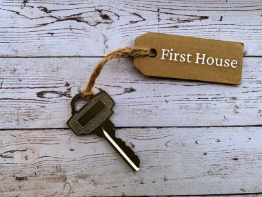 Kahverengi etiketli, ev anahtarı ve ahşap masa arkaplanlı yazı. Özellik kavramı.