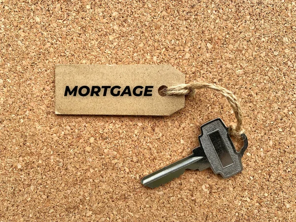 带有房屋钥匙和木制桌子背景的褐色标签文字.抵押贷款.财产概念. — 图库照片