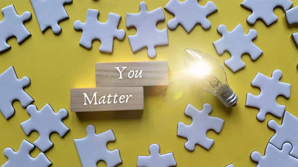 Top view of words - You matter with light bulb and jigsaw puzzle background. — Stock Photo, Image