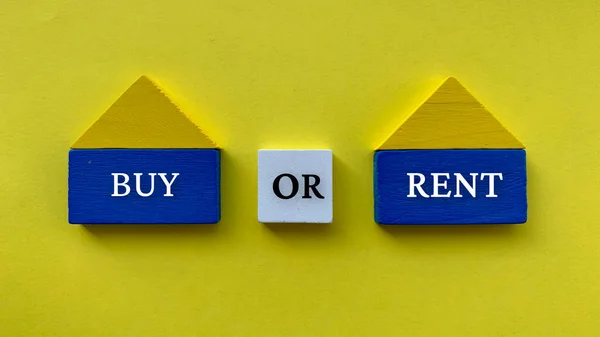 Koop of huur tekst op houten huis model met gele kleur papier achtergrond. Begrip vastgoedbelegging. — Stockfoto