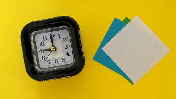 Top view of sticky note and alarm clock with yellow color background. — Stock Photo, Image