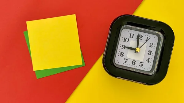Top view of sticky note and alarm clock with red and yellow color background. — Stock Photo, Image